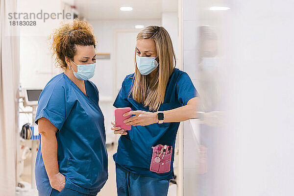 Krankenschwestern diskutieren und nutzen Smartphones im Krankenhaus