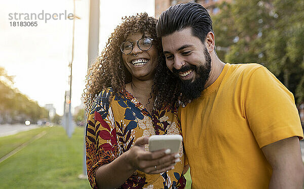 Glückliche junge Frau zeigt ihrem Freund ihr Smartphone