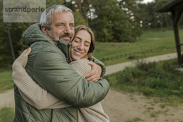 Nachdenklicher Vater umarmt glückliche Tochter