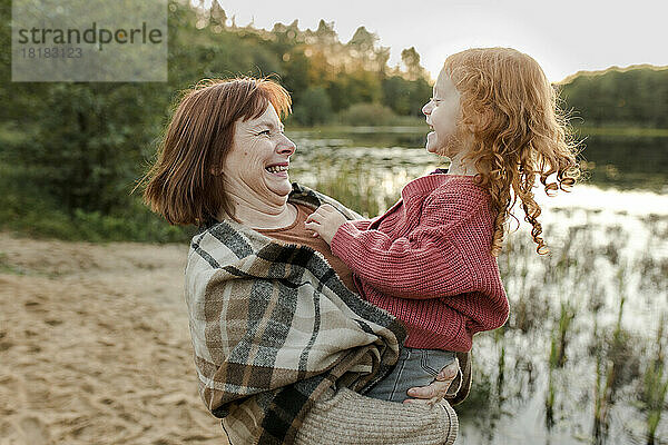 Glückliche Großmutter  die mit Enkelin am See spielt