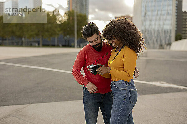 Junge Frau zeigt ihrem Freund am Fußweg die Kamera
