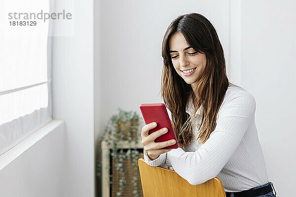 Lächelnde Frau  die zu Hause ihr Smartphone benutzt