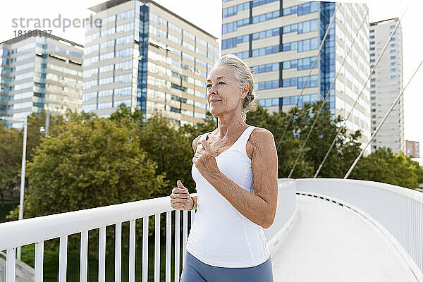 Reife Frau joggt auf Fußgängerbrücke