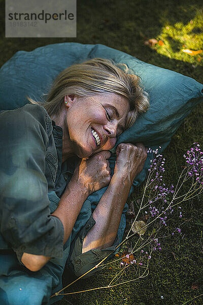 Happy mature woman sleeping in garden
