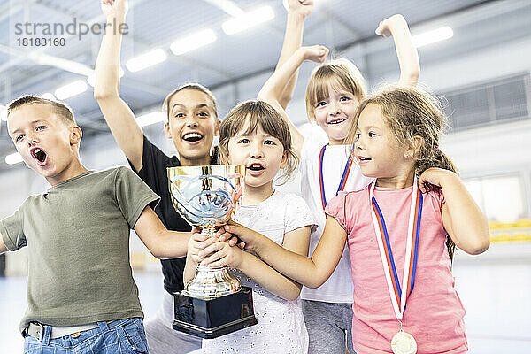 Fröhliche Schüler feiern Sieg mit Lehrer am Schulsportplatz