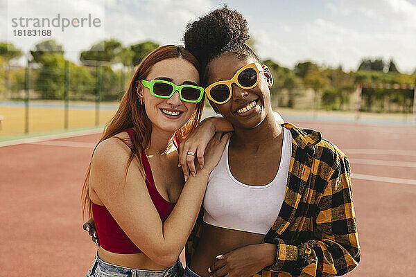Junge Frauen mit Sonnenbrille stehen auf dem Sportplatz