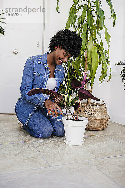 Lächelnde junge Frau  die Pflanze gießt