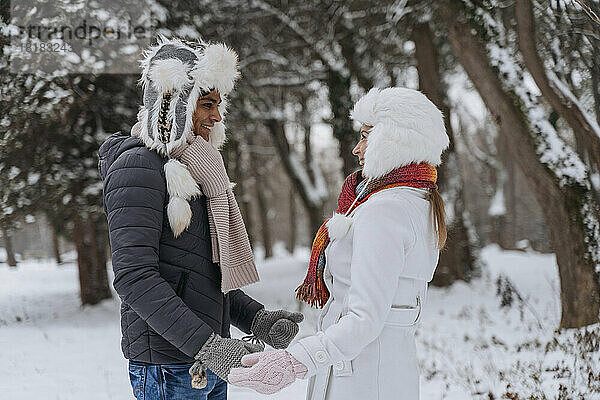 Glücklicher junger Mann und Frau stehen im Winter im Park