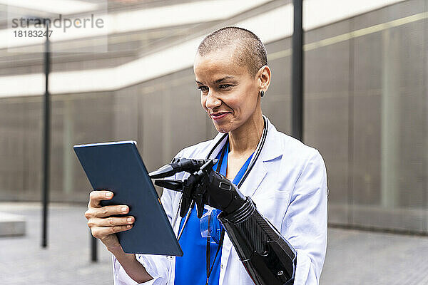 Lächelnde Ärztin mit Tablet-PC und künstlicher Hand