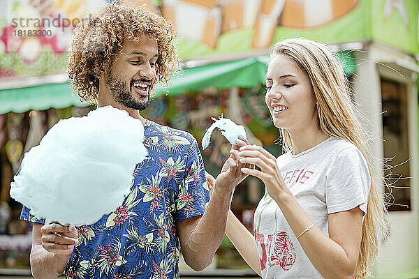 Young couple eating candy floss at a fun fair