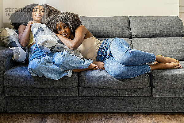 Gemischtrassige Freundinnen entspannen sich zu Hause auf dem Sofa