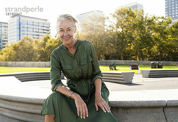 Lächelnde reife Frau auf Bank im Park