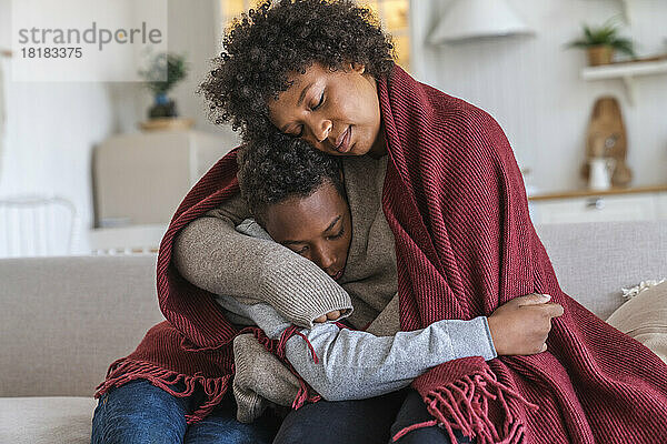 Mutter umarmt Sohn zu Hause in Decke gehüllt