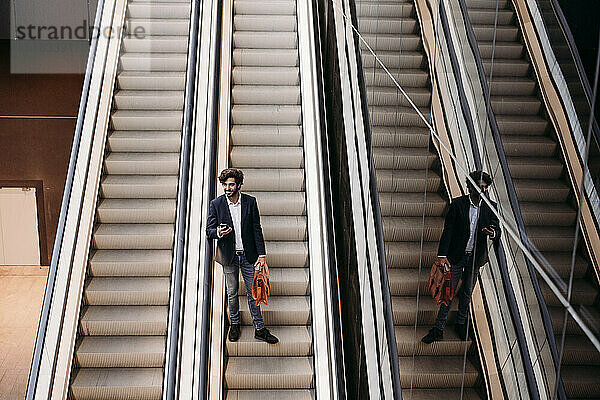 Geschäftsmann hält Tasche in der Hand und bewegt sich von der Rolltreppe nach unten