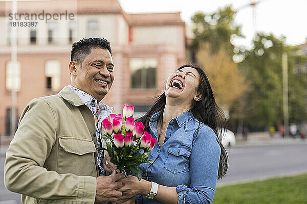 Glückliches älteres Paar hält am Valentinstag Blumen vor dem Gebäude