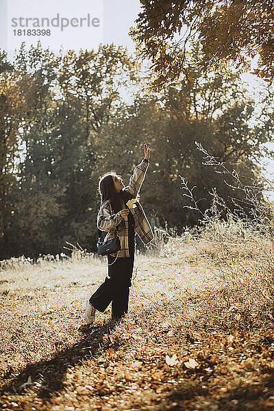 Mädchen mit erhobener Hand steht im Herbstwald