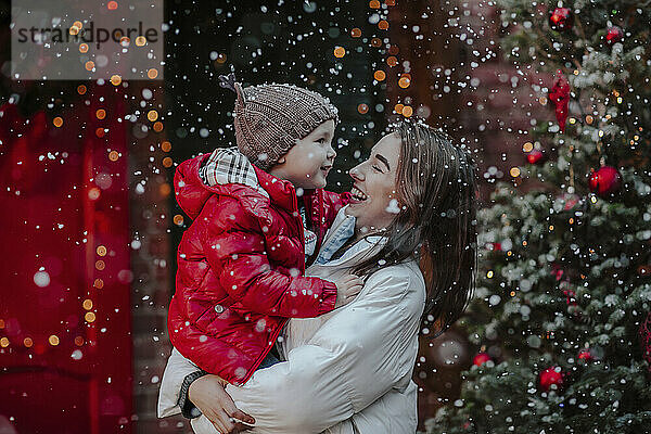 Fröhliche Frau mit Sohn genießt den Schnee