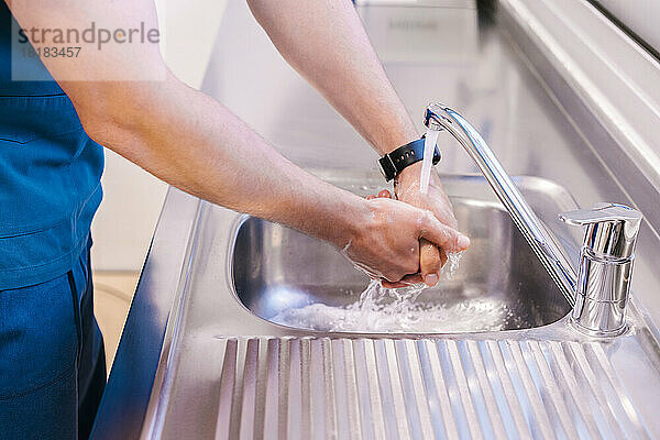 Junger Arzt wäscht im Waschbecken im Krankenhaus die Hände mit Wasser