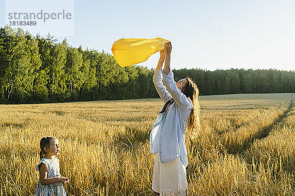Mädchen mit verspielter Mutter hält Müllsack auf dem Feld