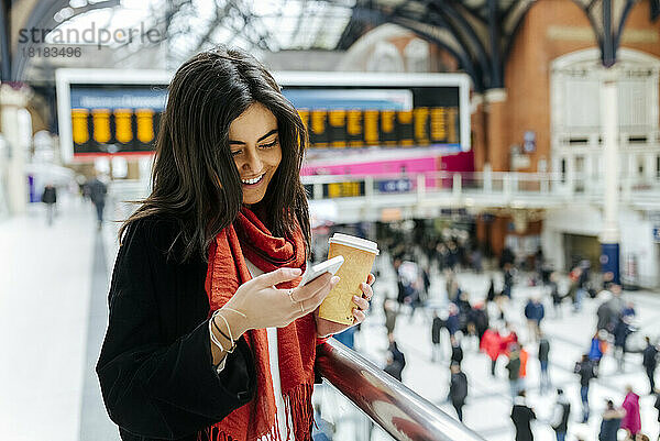 Großbritannien  London  junge Frau benutzt Mobiltelefon am Bahnhof