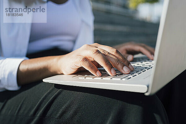 Hände einer jungen Frau  die einen Laptop benutzt