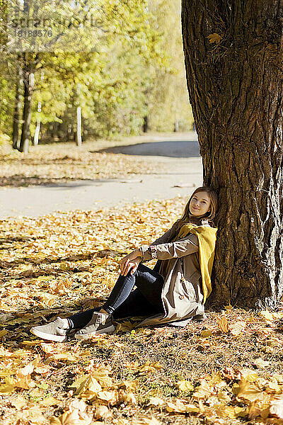 Frau lehnt an einem sonnigen Tag an einem Baum im Park