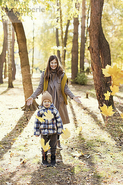 Mutter bewirft Sohn im Park mit Herbstlaub