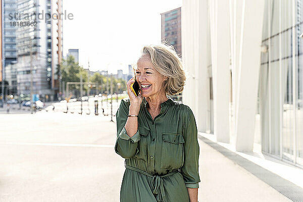 Lächelnde reife Frau  die auf dem Smartphone spricht