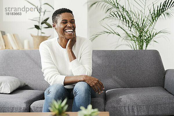 Laughing woman sitting on couch at home
