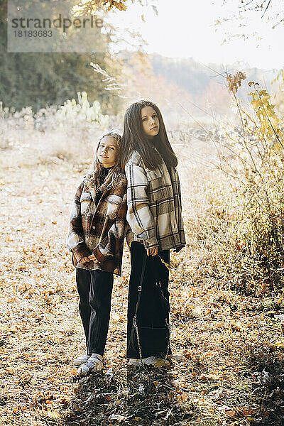 Mädchen mit Schwester steht im Herbstwald