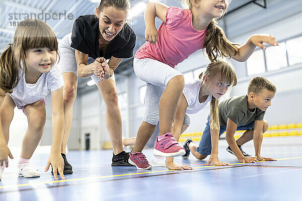 Mädchen startet Rennen mit Freunden  während Lehrer im Hintergrund jubeln