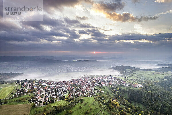 Deutschland  Baden-Württemberg  Drohnenansicht von Wolken über dem Dorf im Remstal bei nebligem Herbstsonnenaufgang