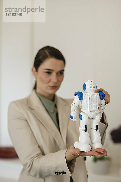 Geschäftsfrau analysiert Spielzeugroboter im Büro