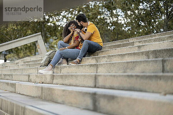 Happy young couple sitting on steps spending leisure time together
