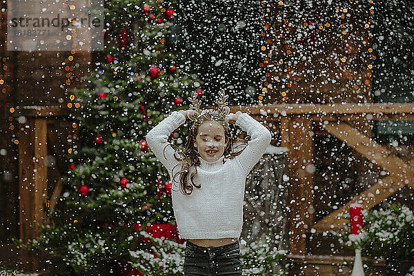 Fröhliches Mädchen genießt den Schneefall im Vorgarten
