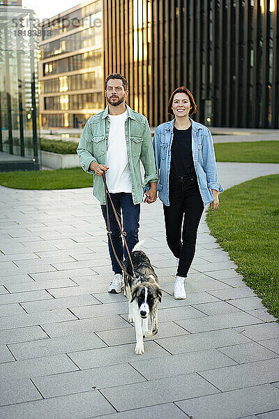 Mann und Frau spazieren mit Hund auf Fußweg
