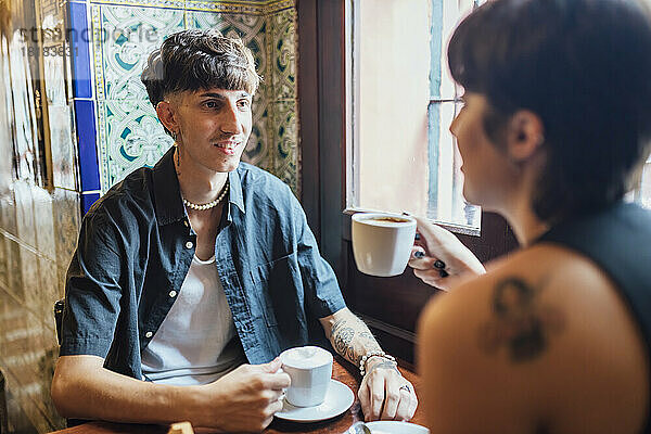 Hipster-Mann blickt Freundin mit Kaffeetasse im Café an