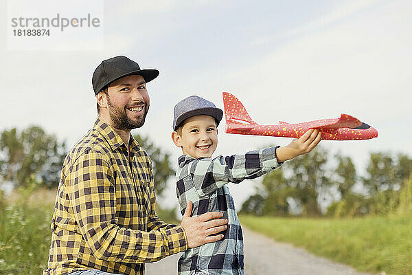 Lächelnder Vater und Sohn mit Spielzeugflugzeug in karierten Hemden