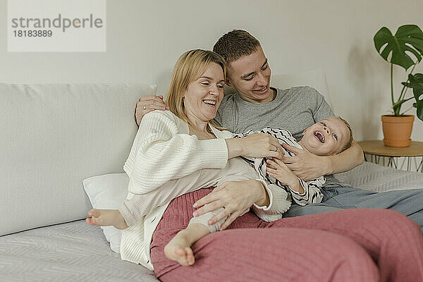 Glückliche Mutter und Vater genießen es mit ihrem Sohn zu Hause auf dem Sofa
