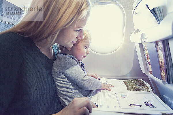 Mutter mit Sohn im Flugzeug liest Zeitschrift