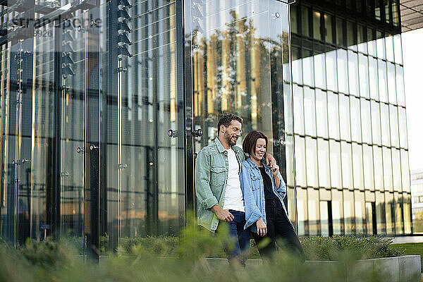Glückliches Paar lehnt an der Glaswand des Gebäudes