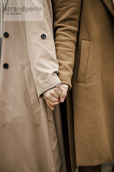 Women wearing overcoats holding hands
