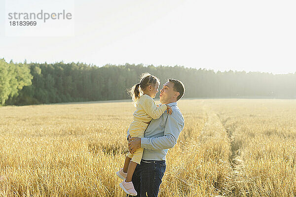 Vater trägt Tochter an sonnigem Tag im Feld