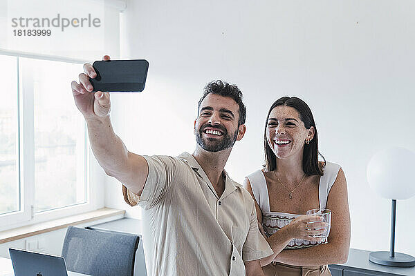 Glückliche Geschäftsleute  die im Büro Selfies per Smartphone machen
