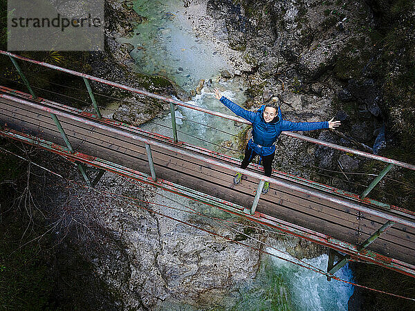 Austria  Lower Austria  Annaberg  Drone view of female hiker standing with raised arms on bridge stretching over Otscherbach river