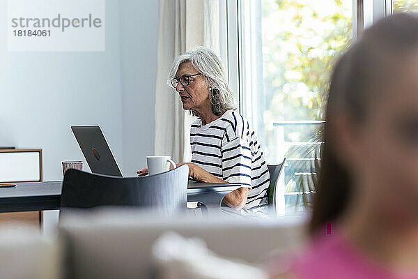 Ältere Frau benutzt Laptop am Tisch zu Hause