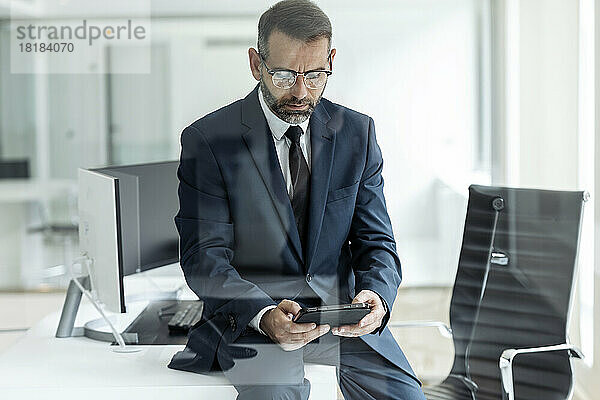 Geschäftsmann sitzt am Tisch im Büro und benutzt einen Tablet-PC