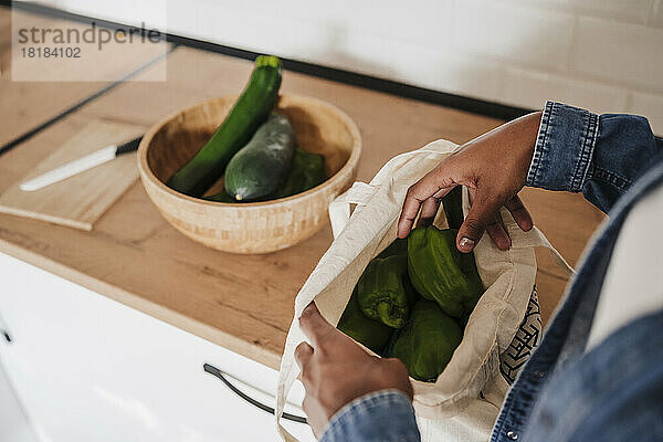 Hände einer Frau  die Gemüse aus der Tüte an der Küchentheke nimmt