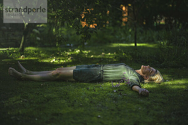 Woman with arms outstretched lying on grass