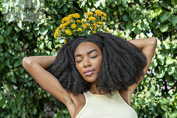 Frau mit geschlossenen Augen hält gelbe Blumen vor der Pflanze